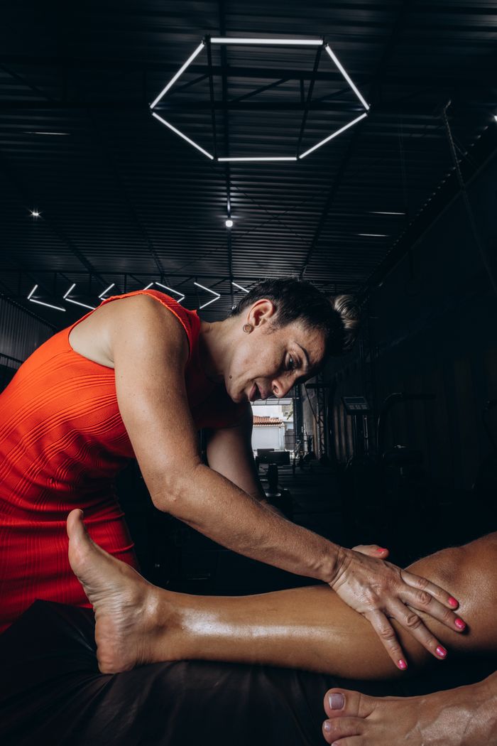 Massage therapist working on client's leg in a gym setting.