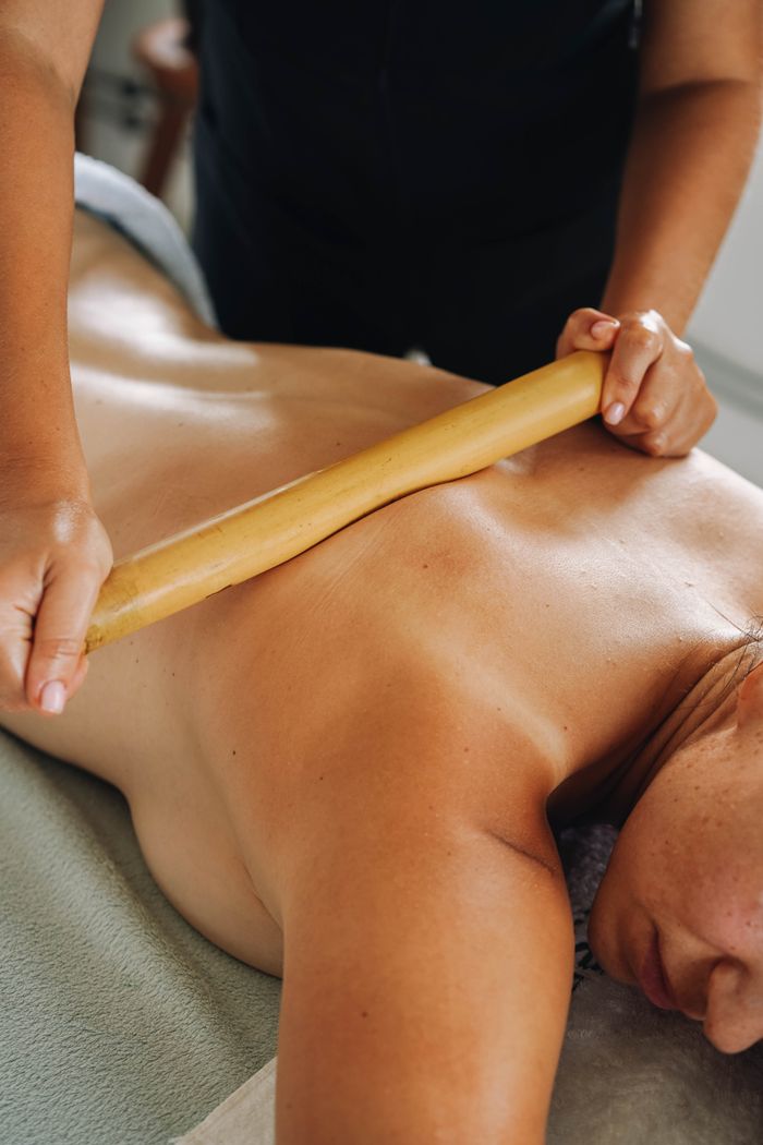 Close-up of a woman enjoying a soothing bamboo massage in a spa setting.